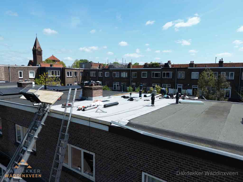 Dakdekkers aan het werk op plat dak in Waddinxveen